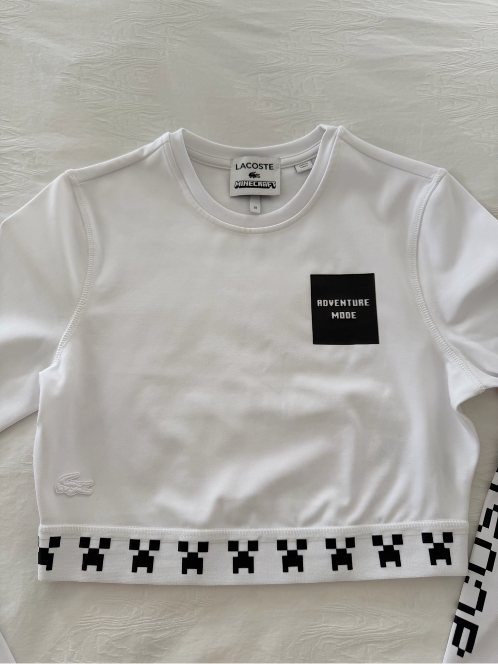 Lacoste White Crop Top with Black 'Adventure Mode' Patch